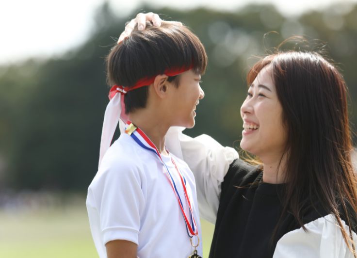 子供を褒める母親と男子学生