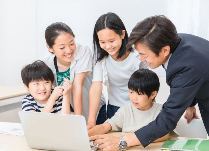 教室でグループワークを行う生徒4人と教師