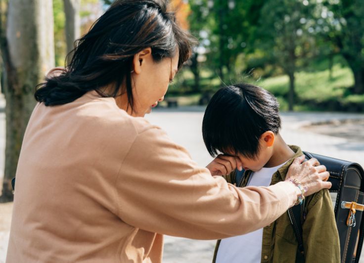 泣いている男子小学生と母親
