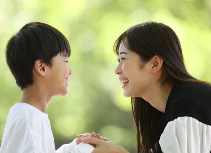 笑顔で顔を見合う子供と母親
