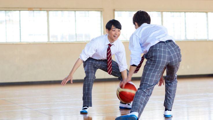バスケットボールをする男子学生