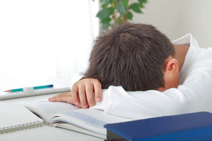 勉強中に居眠りする少年