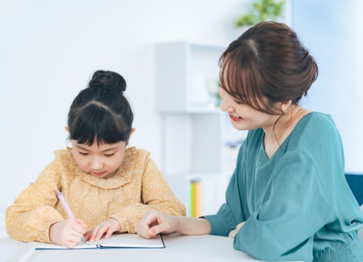 勉強中の少女をサポートする女性