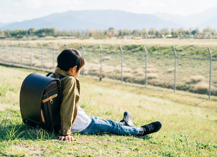 勉強につかれて川辺で休んでいる男の子